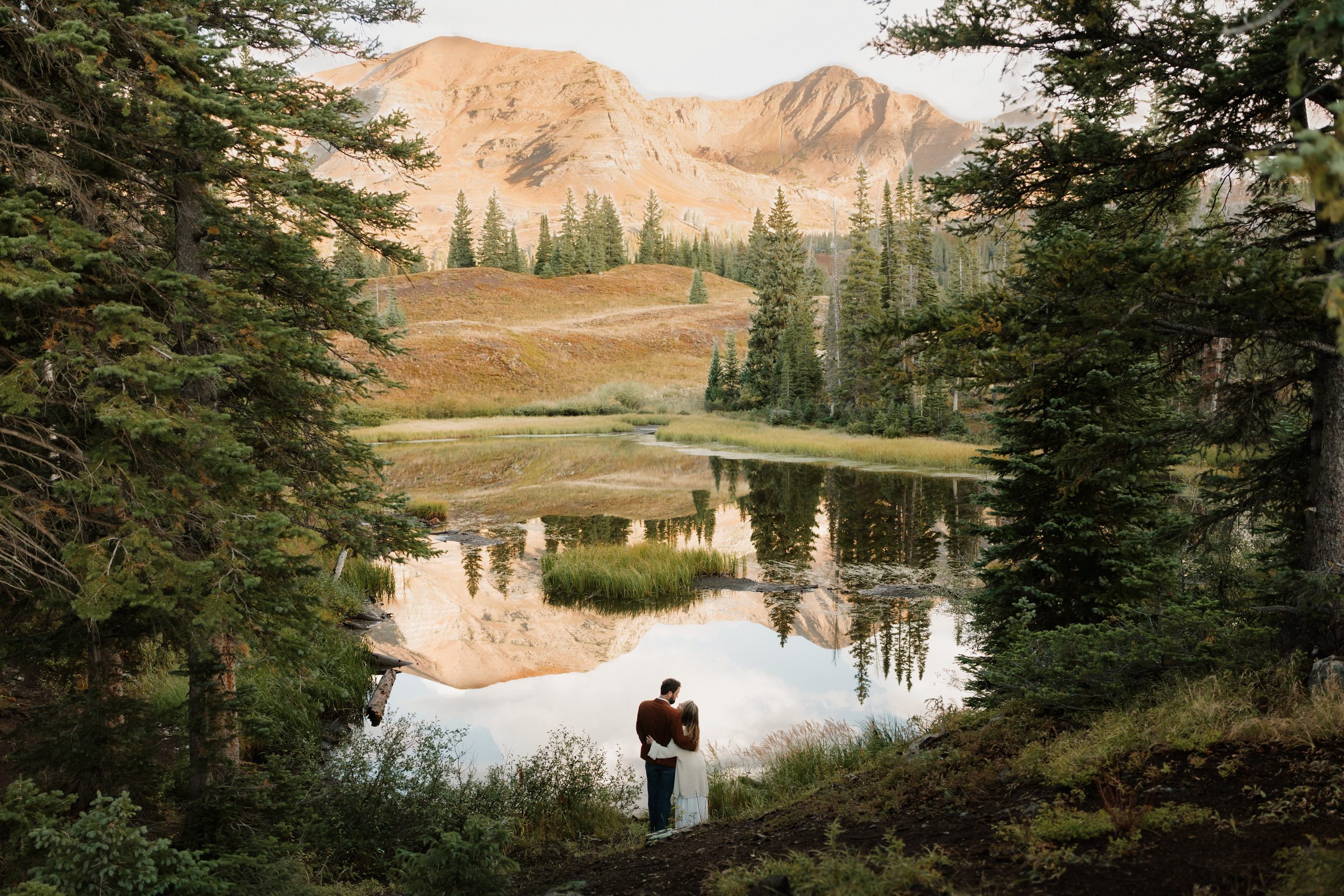 Couple standing beside a scenic mountain lake during a Colorado engagement session