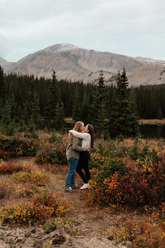 Colorado Engagement Session Locations Couple embracing beside Brainard Lake with mountain views during their Colorado engagement session