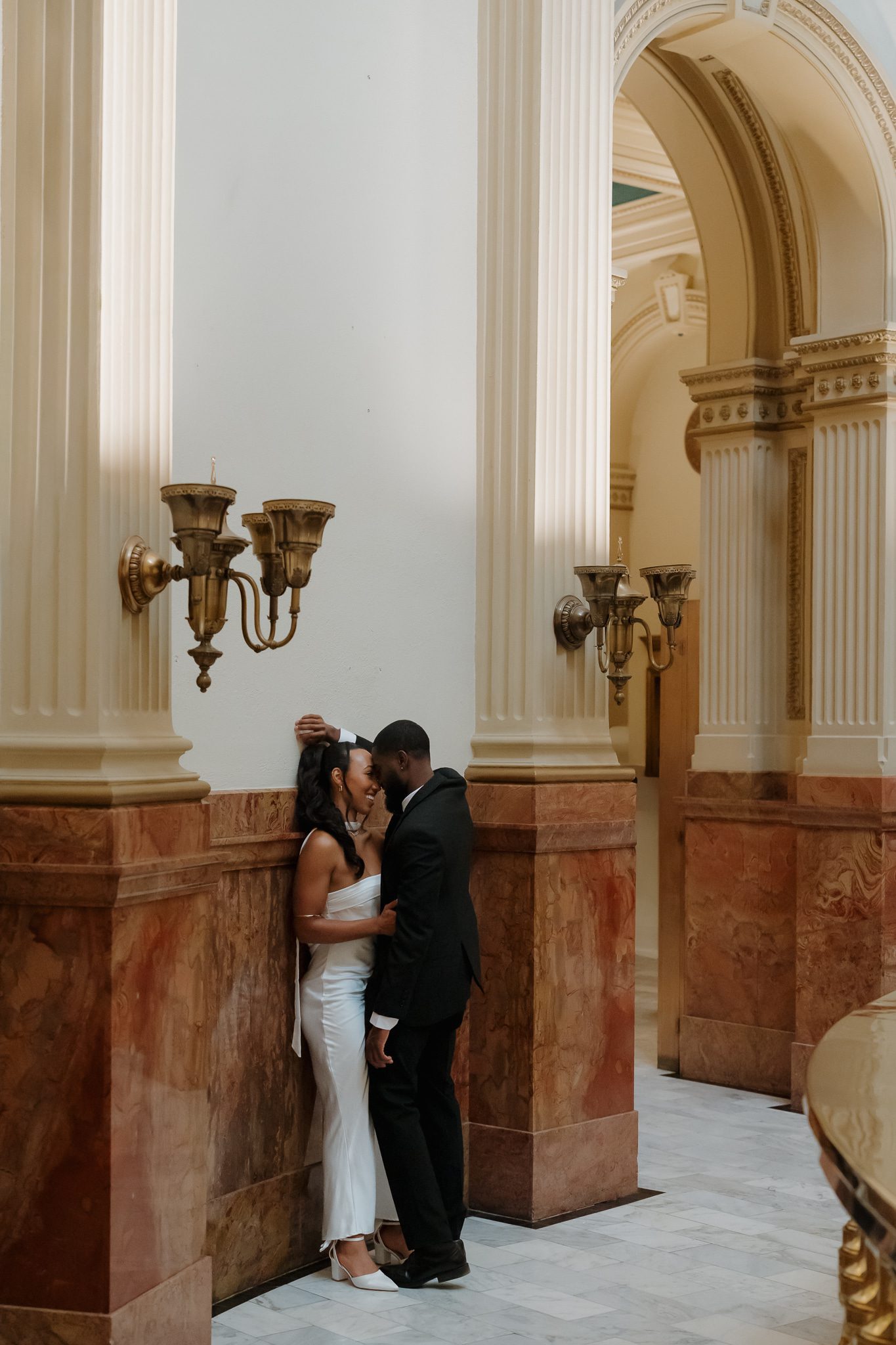 Colorado Engagement Session Locations Couple kissing near vintage architectural details during their downtown Denver Colorado engagement session