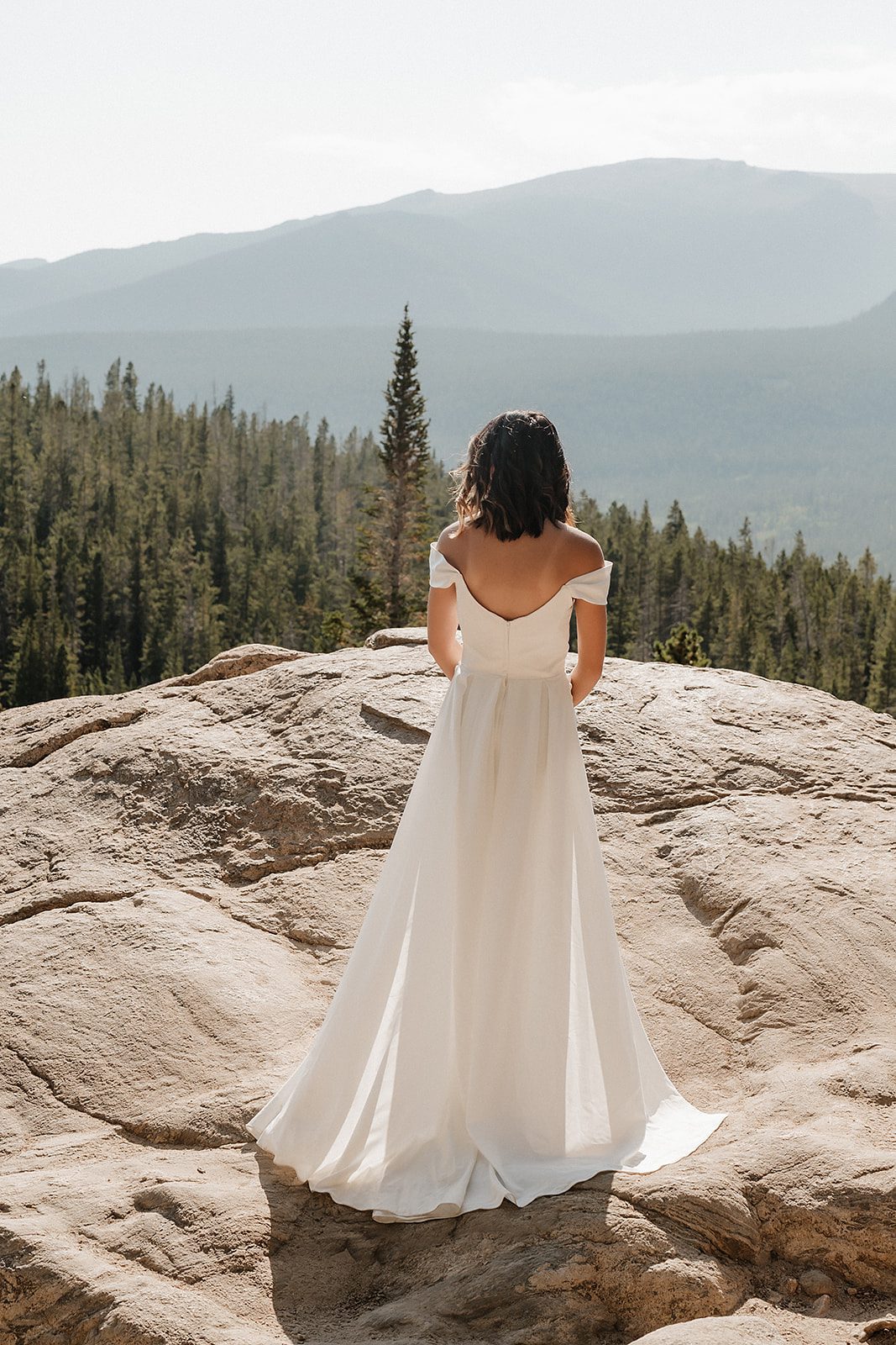 Rocky Mountain National Park elopement bride in off-shoulder gown looking out over the Colorado mountain valley