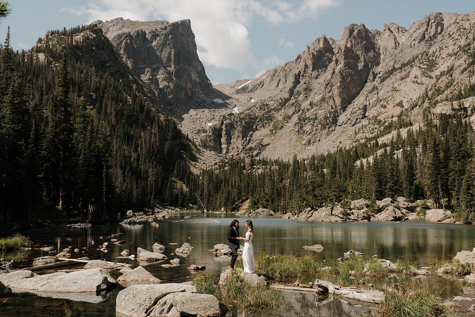 Rocky Mountain National Park elopement couple reading vows at Dream Lake with turquoise water and dramatic peaks behind them